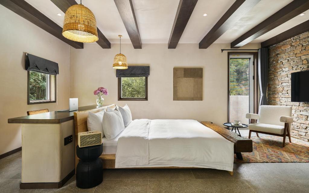 a bedroom with a bed and a stone wall at Yangshuo One Thousand and One Courtyard Views B&B in Yangshuo