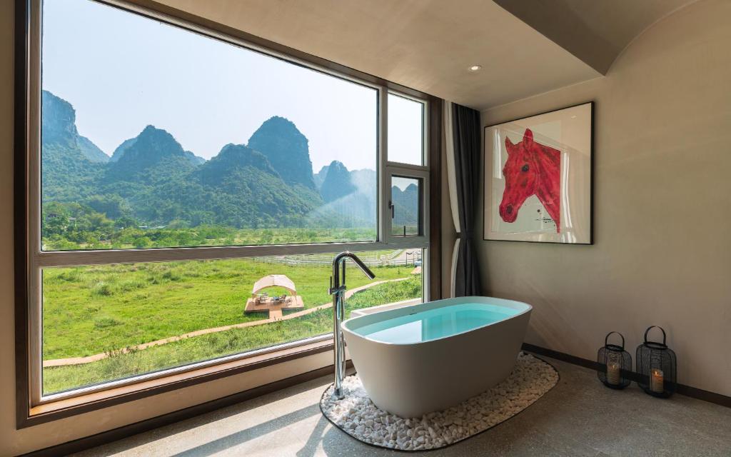a bathroom with a large window and a bath tub at Yangshuo One Thousand and One Courtyard Views B&B in Yangshuo