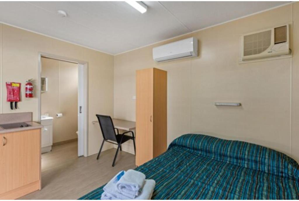 a bedroom with a bed and a desk and a table at Discovery Parks - Blackwater in Blackwater