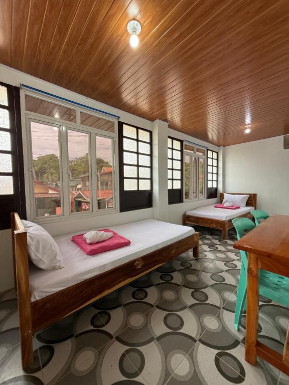 a room with two beds and a table and windows at Agoo Tourist Cabin in Agoo