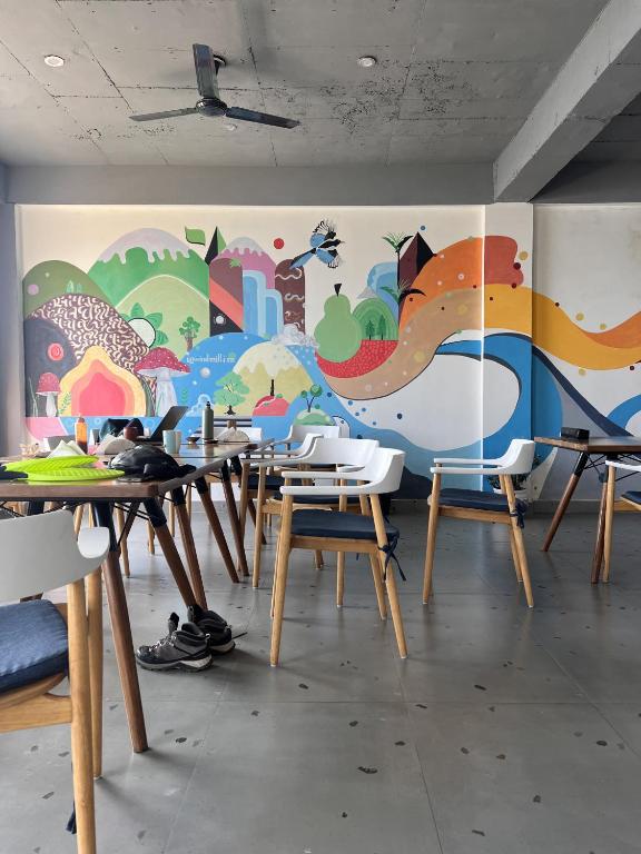 a room with tables and chairs with a mural on the wall at Windmill Inn in Solan