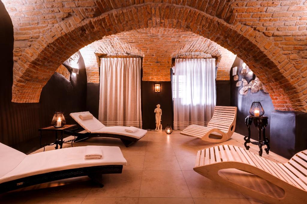 Vaulted brick relaxation chamber with multiple wooden loungers, soft curtains and ambient lighting.