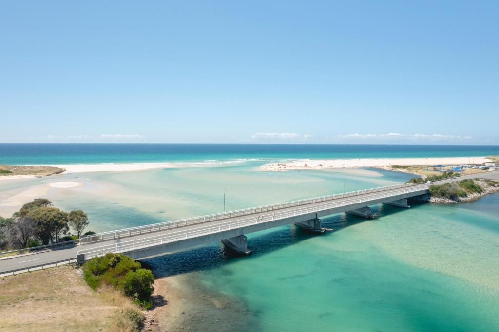a bridge over the water next to a beach at Blue Seas Holiday Villas in Scamander
