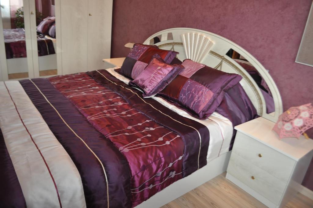 una camera da letto con un grande letto con lenzuola e cuscini viola di LD apartamenti a Ventspils