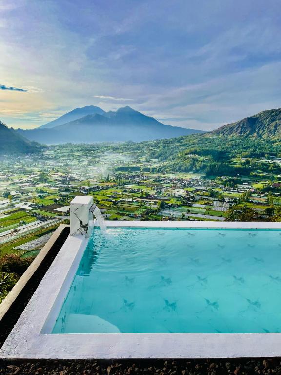 a swimming pool with a view of a city and mountains at pinggan box glamping in Bangli