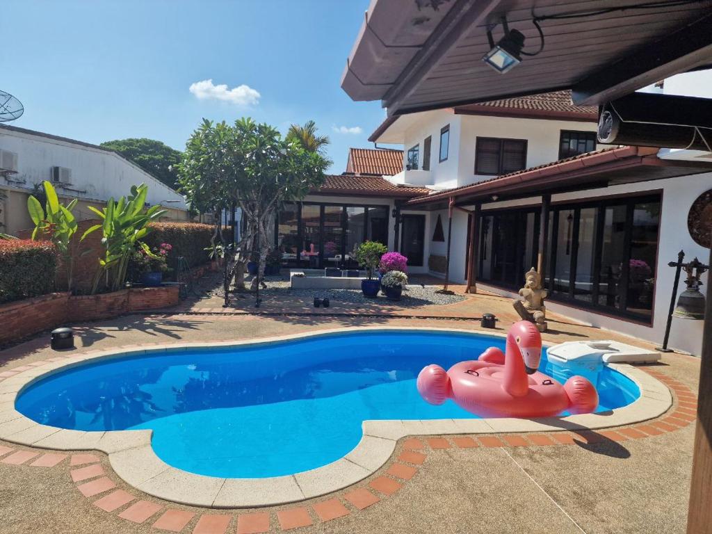 Una piscina con un juguete inflable frente a una casa. en Very cozy room, en Ban Klang