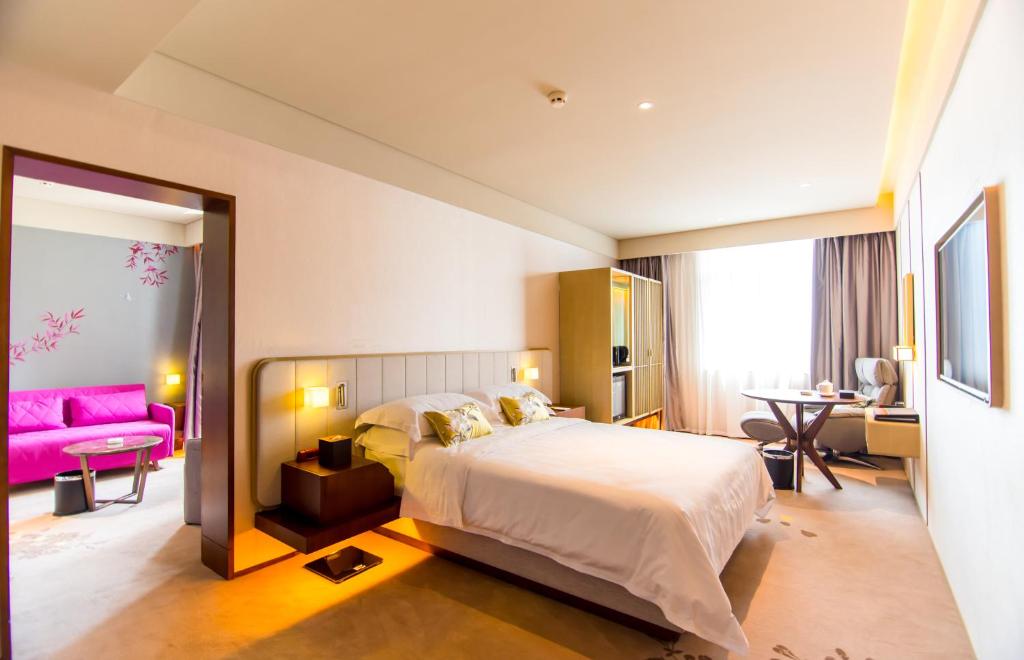 a bedroom with a large bed and a pink couch at 威海卫大厦 Weihaiwei Hotel in Weihai
