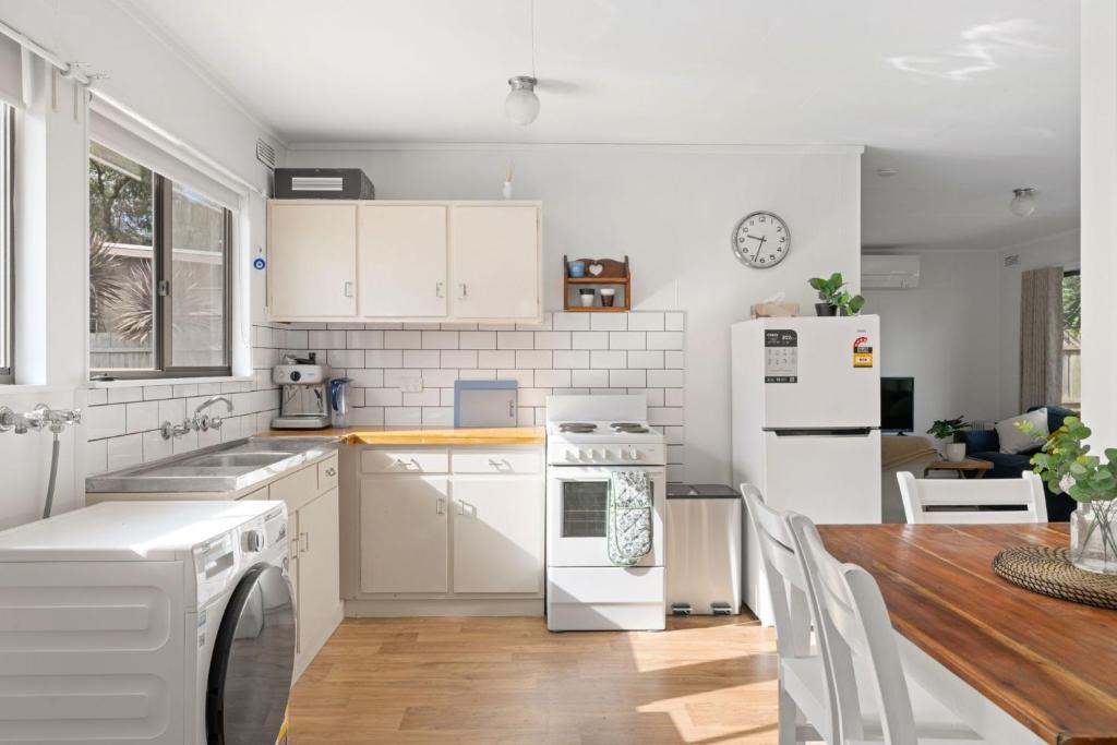 a kitchen with white appliances and a wooden table at Little Pier Cottage in Inverloch