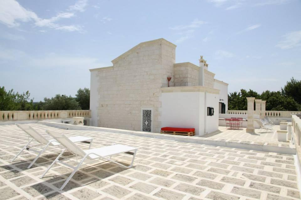 a pair of lounge chairs on a stone patio at Masseria Conca D'Oro in Ostuni