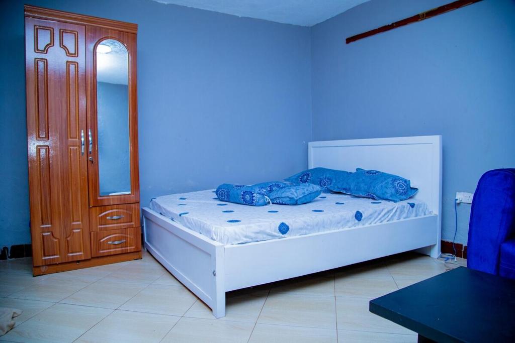 a bedroom with a white bed with blue walls at Cozy Studio Apartment Makindye in Kampala