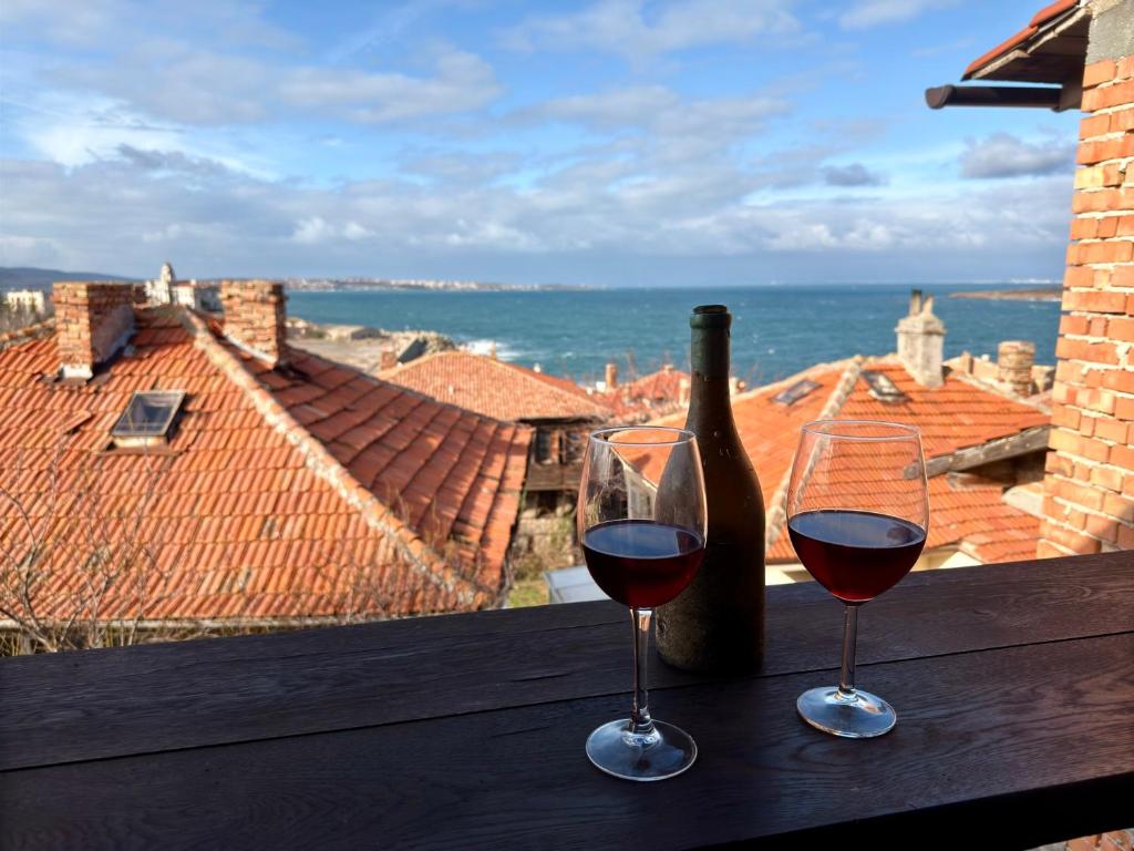 dos copas de vino sentadas en una mesa con una botella de vino en Arthotel Oscar I Sozopol, en Sozopol