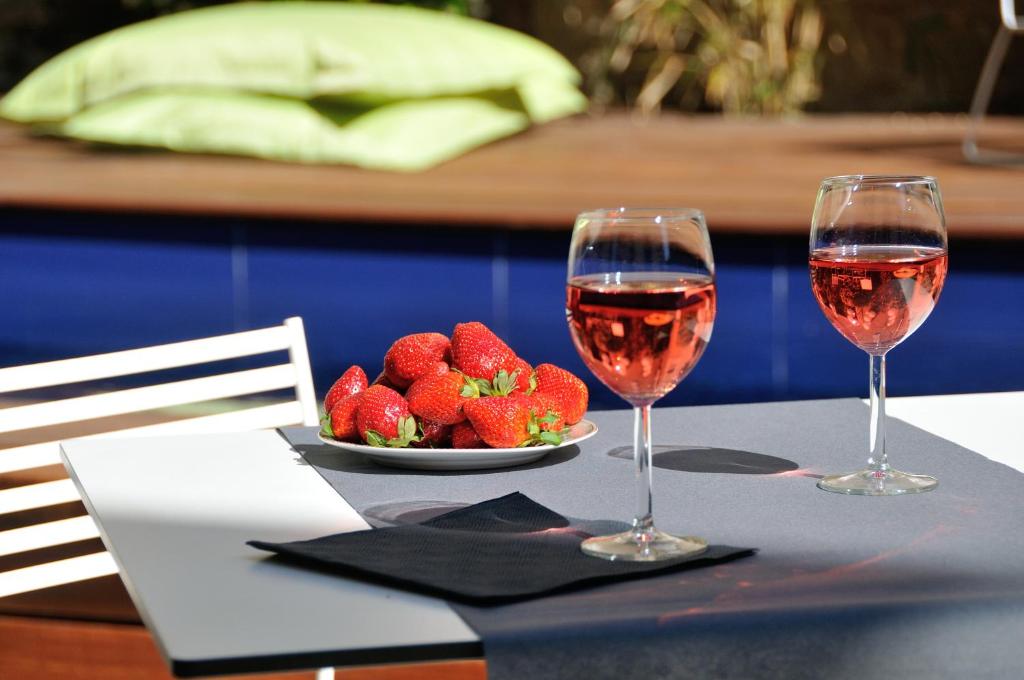 two glasses of wine and a plate of strawberries on a table at L'Hôtel Particulier Beziers in Béziers