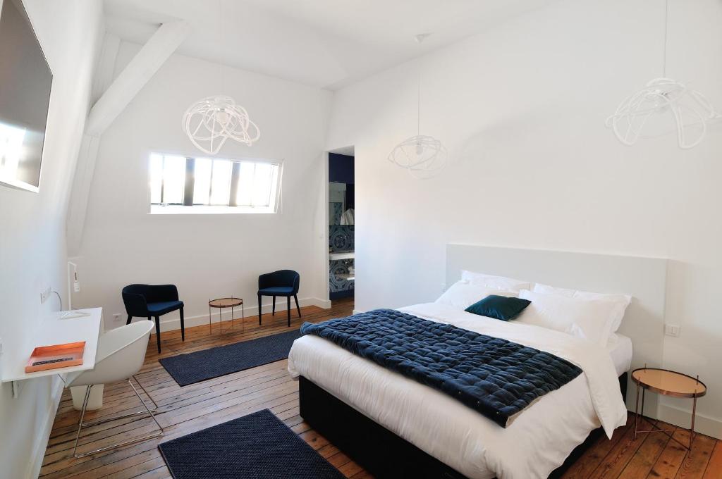 a bedroom with a large bed and two chairs at L'Hôtel Particulier Beziers in Béziers