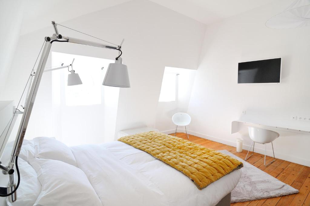 a white bedroom with a bed and a lamp at L'Hôtel Particulier Beziers in Béziers