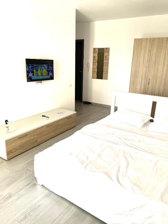 a white bedroom with a bed and a tv on the wall at Vitan Marvel in Bucharest