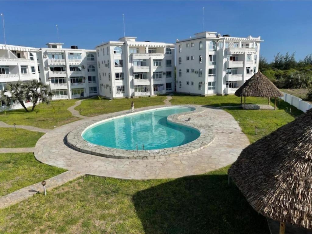 a swimming pool in front of a large apartment building at Tulip Serenity in Malindi