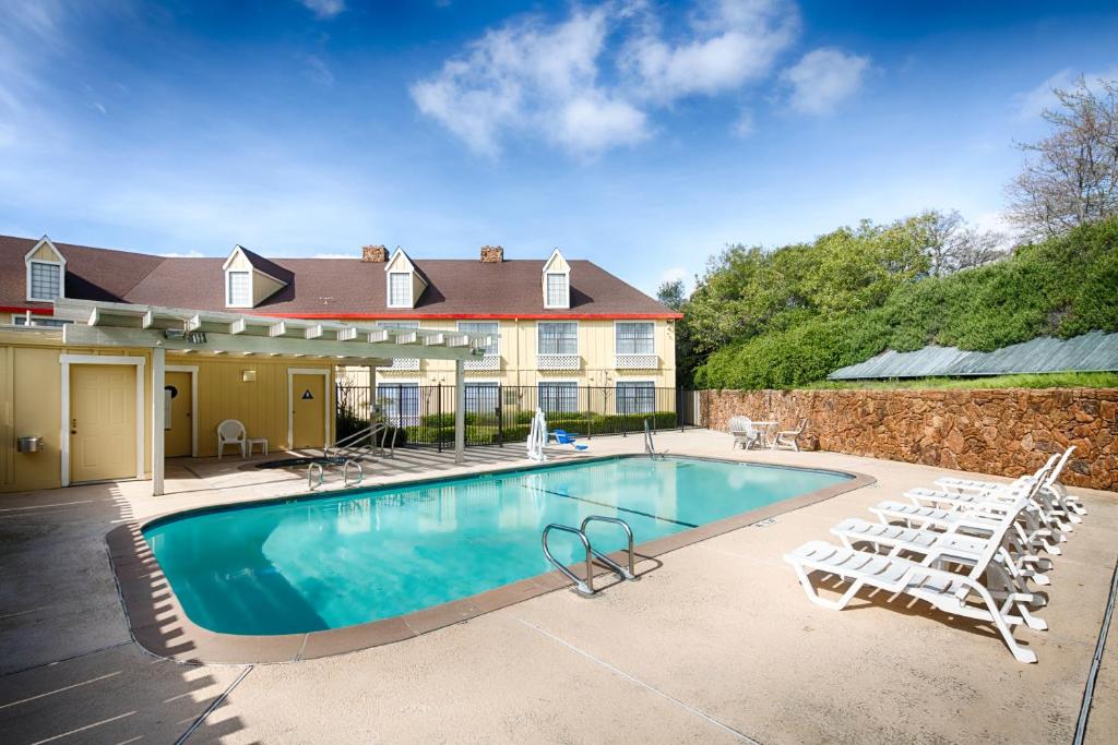a swimming pool with lounge chairs and a house at Red Lion Inn & Suites Auburn in Auburn
