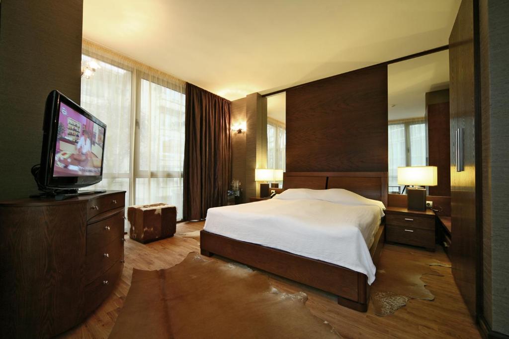 Hotel City Pleven في بليفين: غرفة نوم بسرير وتلفزيون بشاشة مسطحة