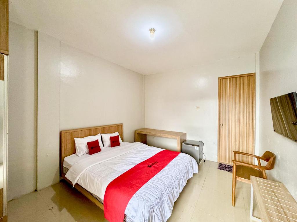 une chambre avec un grand lit avec une couverture rouge dans l'établissement RedDoorz Syariah Near Maguwoharjo Yogyakarta, à Seturan