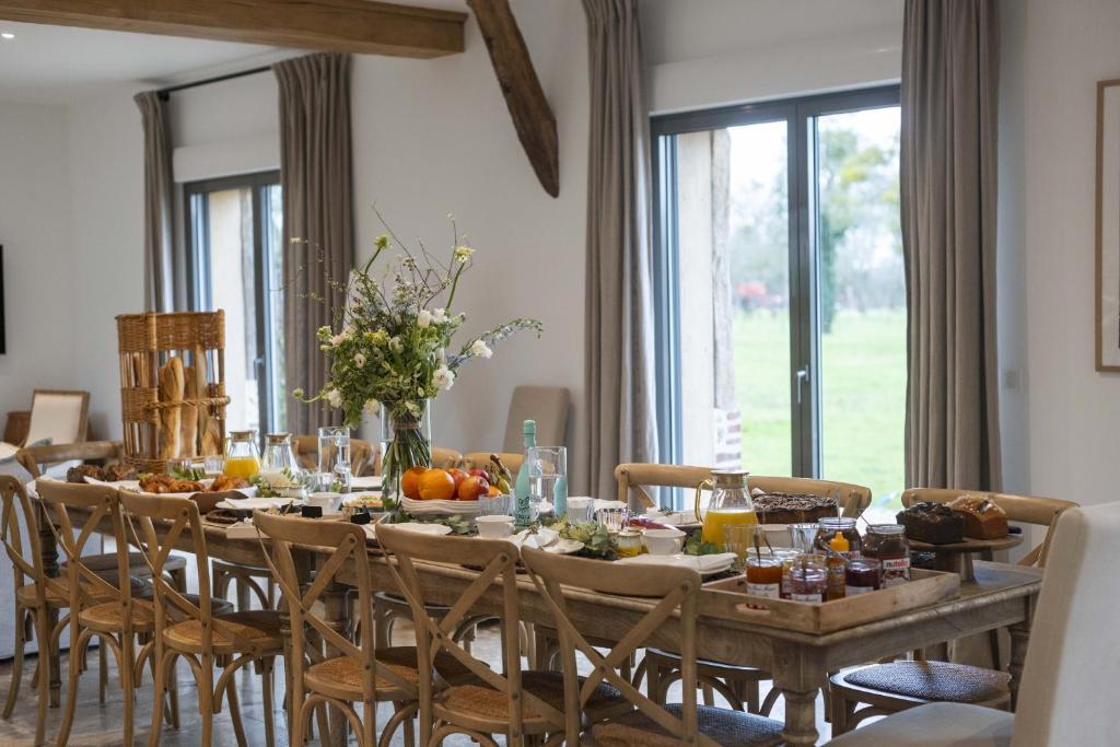 une salle à manger avec une grande table et de la nourriture dans l'établissement Maison des Pommiers Elegant house near Deauville, à Cricquebœuf