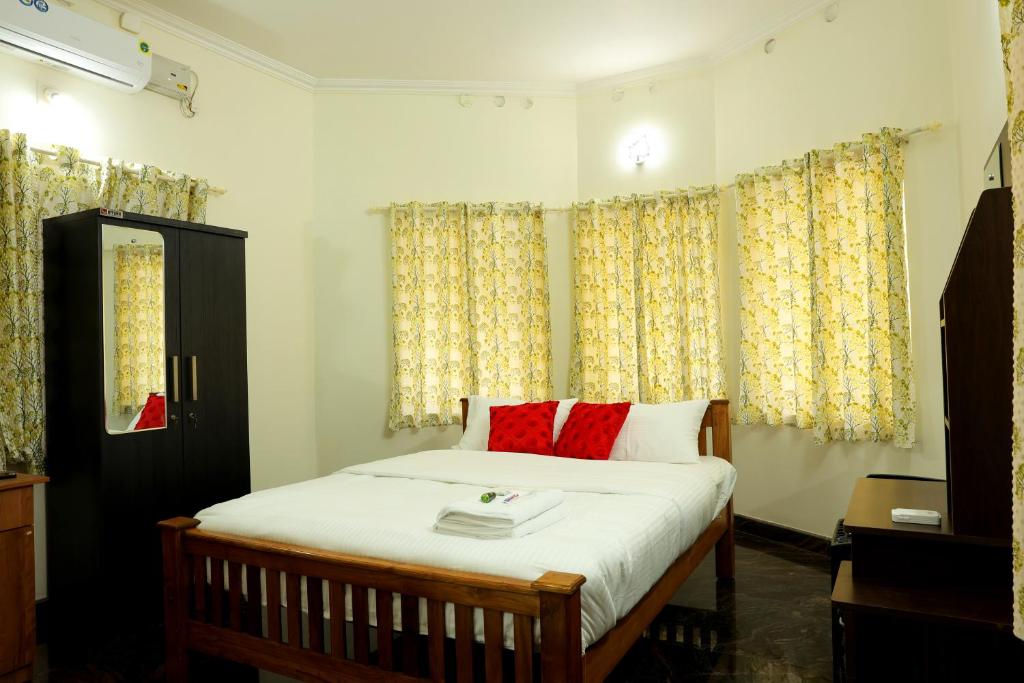 a bedroom with a bed with red pillows at Kunnumpurathu Holidays & Homestay in Kottayam
