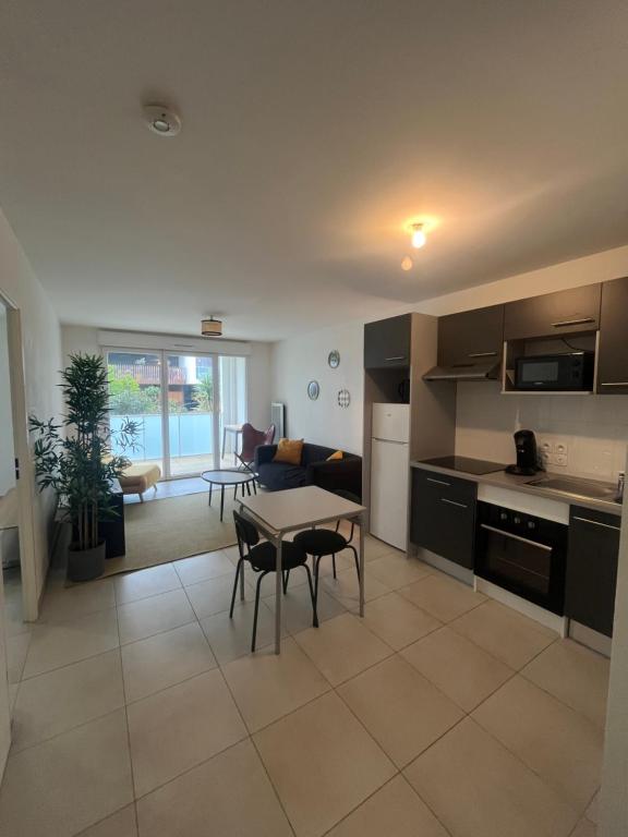 une cuisine et un salon avec une table et des chaises dans l'établissement Joli T2 Terrasse Parking privé Confort, à Montpellier