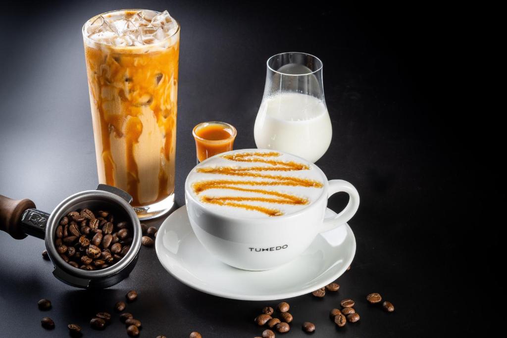 A promotional coffee still life featuring iced coffee, latte, milk, and roasted beans.