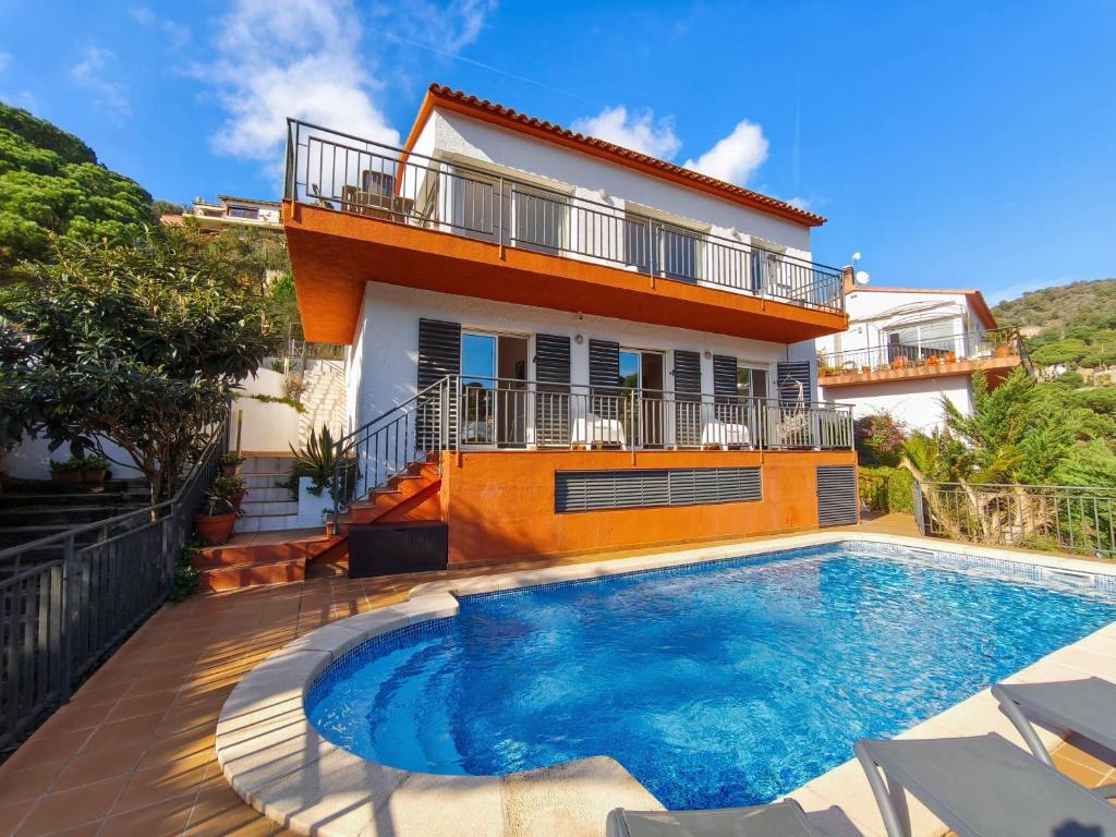 a villa with a swimming pool in front of a house at Pinzon, gezellige familievilla met groot zwembad. in Lloret de Mar