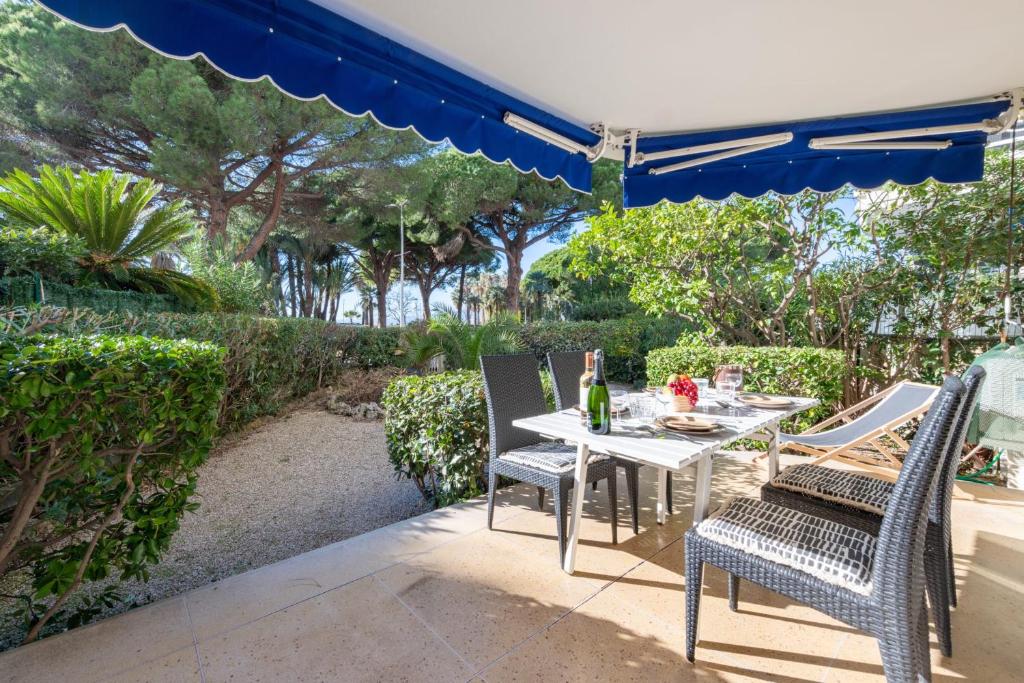 - une table et des chaises sous un parasol sur la terrasse dans l'établissement Garden-Level Apartment in Palm Beach with Garage, à Cannes