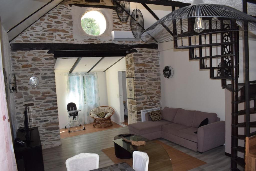 un salon avec un canapé et un mur en pierre dans l'établissement MAISON CLIMATISÉE - Vallée Du Tarn - BORD D'EAU, à Trébas