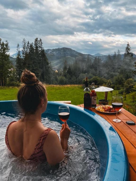 a woman in a hot tub with a glass of wine at Willa Na Polanie z Jacuzzi in Kościelisko