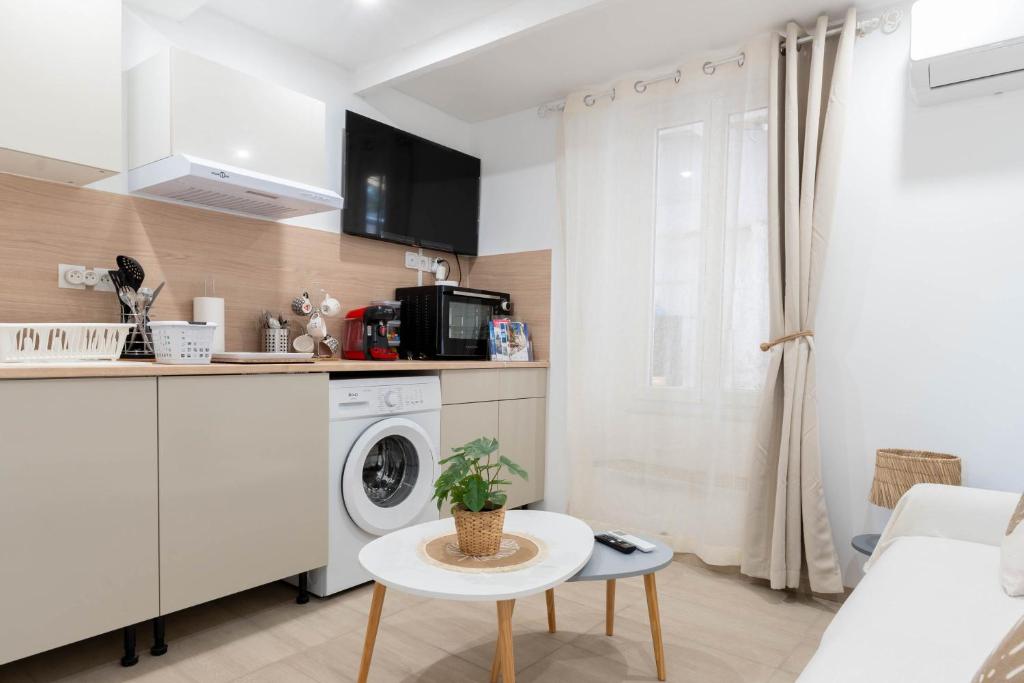 une cuisine avec une machine à laver et une table dans l'établissement L’Espérance dAzur - 500 m de la plage, à Cannes