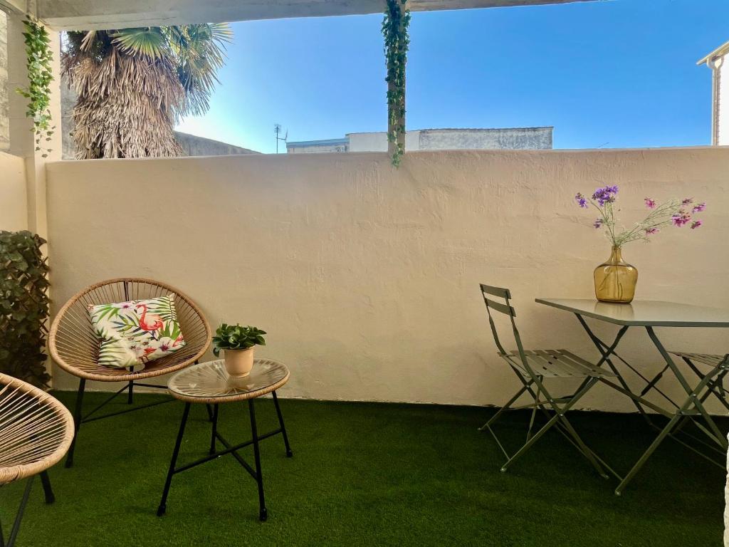 d'une terrasse avec une table, des chaises, une table et un mur. dans l'établissement Escapade Vintage avec terrasse en centre historique, à La Rochelle