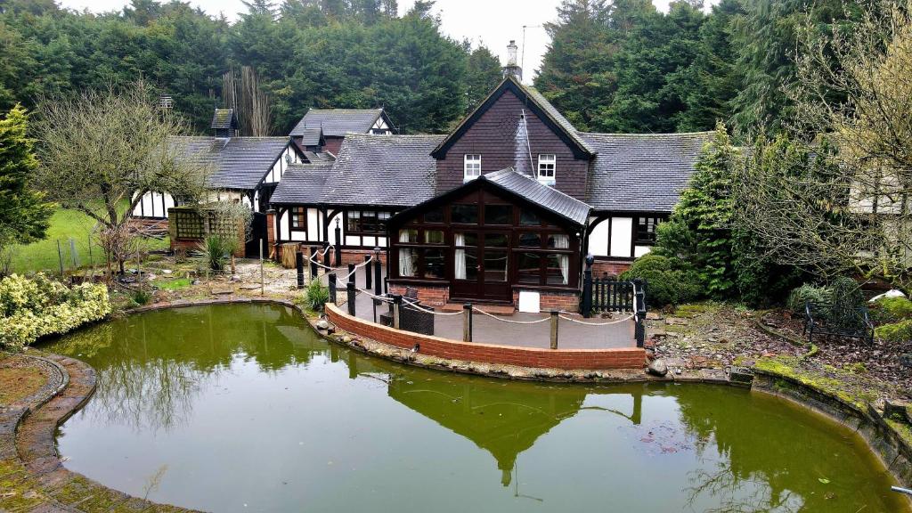 a large house with a pond in front of it at Beautiful cottage in Brentwood in Kelvedon Hatch