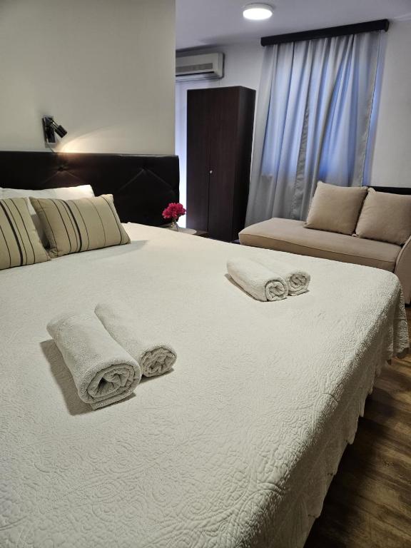 a large white bed with towels and a couch at Hotel Ruža in Međugorje