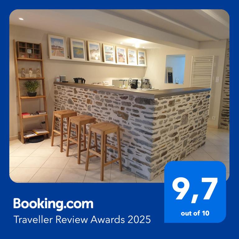 une cuisine avec un comptoir en pierre et des tabourets devant dans l'établissement Maison de ville située à 8 kms du Mont St Michel, à Pontorson