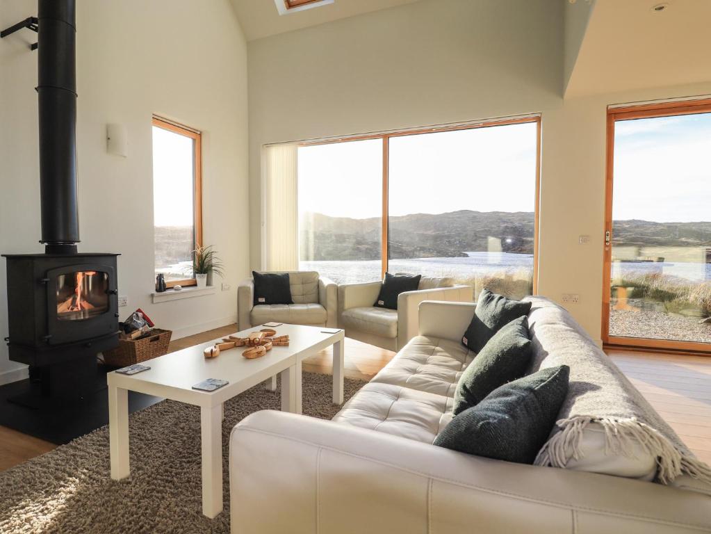 a living room with a white couch and a fireplace at Loch View in Breaclete