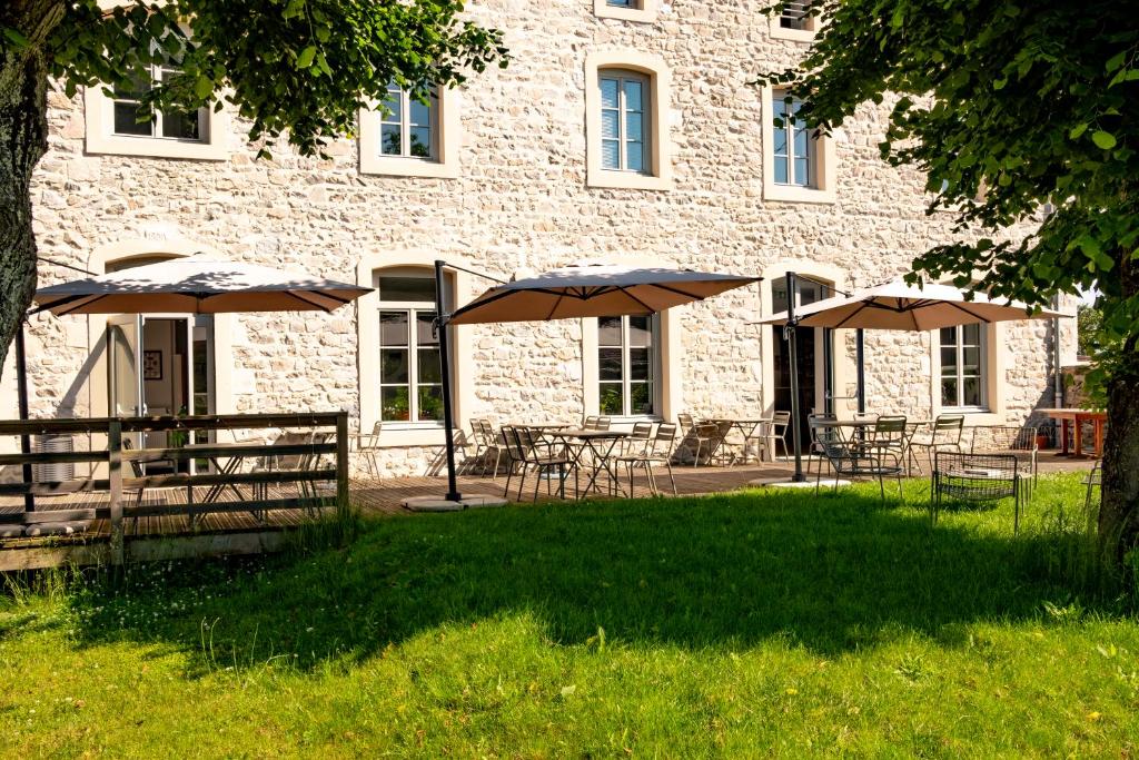 a building with tables and umbrellas in front of it at L'Auberge du Campos in Saint-Pierre-Duchamp