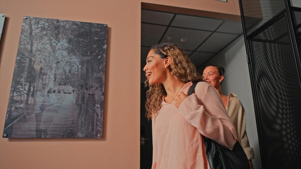 a woman standing in a hallway looking at a painting at Citybox Oslo in Oslo