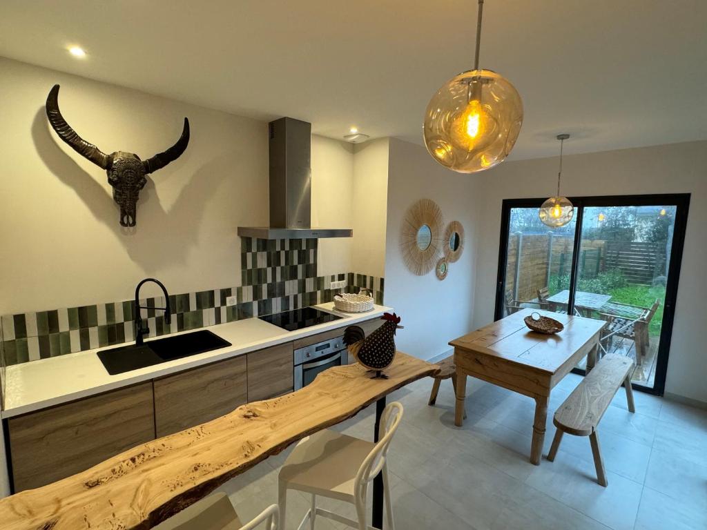 eine Küche mit einem Tisch und eine Küche mit einem Tierkopf an der Wand in der Unterkunft Maison proche bourg et plage in Piriac-sur-Mer