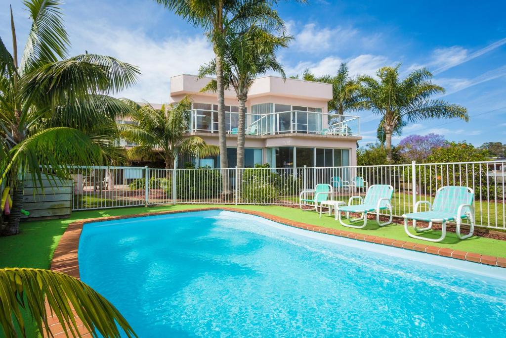 a house with a swimming pool in front of a house at Beach Street Apartments in Merimbula