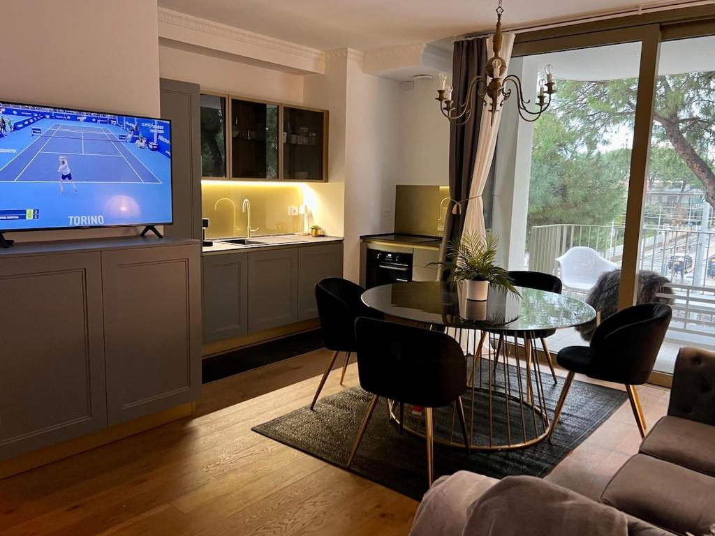 Una sala de estar con televisión, mesa y sillas. en Via Mille House - new trilocale Riccione - centro, en Riccione