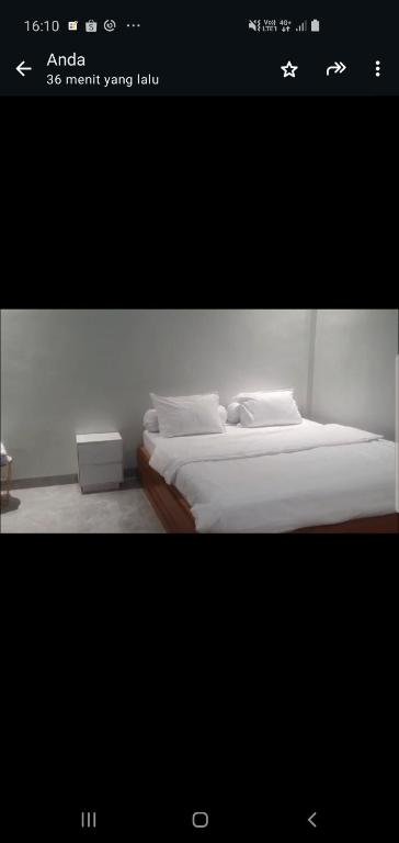 a picture of a bedroom with a bed with white sheets at Daeng Homestay in Pangururan