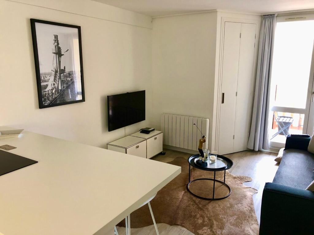 Il comprend un salon doté d'une table blanche et d'une télévision. dans l'établissement Appt familial 5 Pers avec Piscine et Tennis, à Le Touquet-Paris-Plage