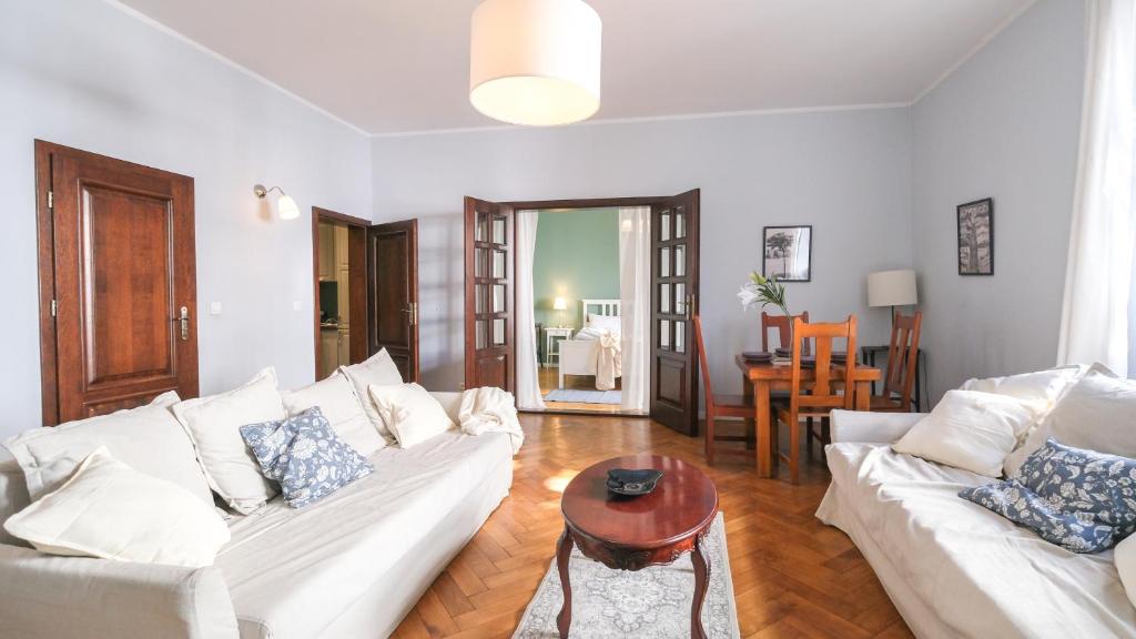 Una sala de estar con dos sofás blancos y una mesa. en Vintage apartments Floriańska street - By Hosty, en Cracovia