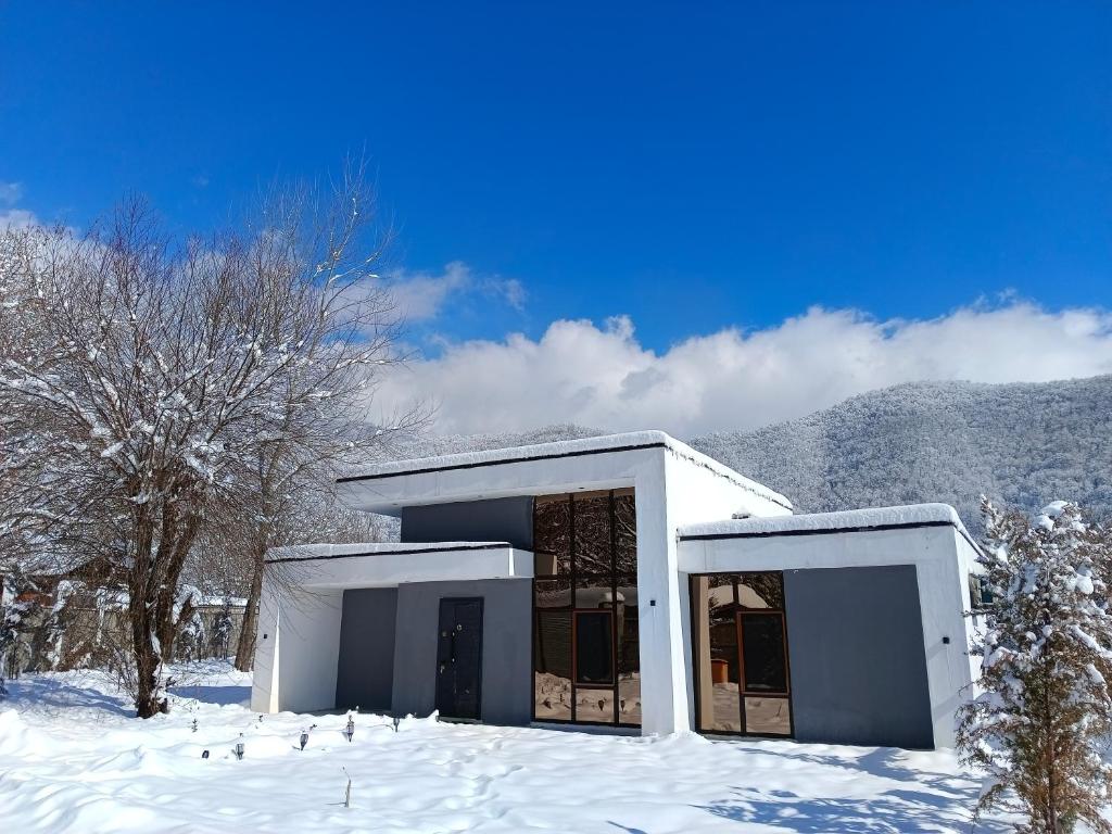 ein weißes Gebäude mit Schnee auf dem Boden in der Unterkunft Harmony Hideaway in Qəbələ