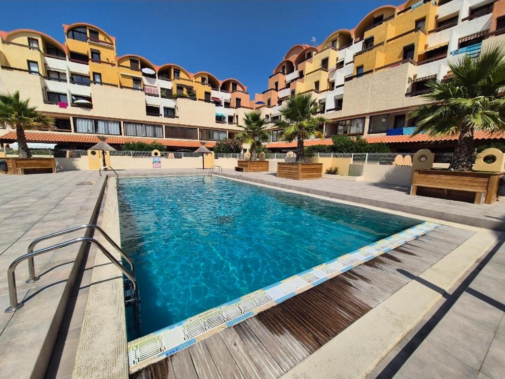 a swimming pool in front of a building at L'Escapade Gruissanaise, appartement 1 chambre, loggia, climatisation, wifi avec piscines de mi-mai à mi-septembre dans résidence in Gruissan