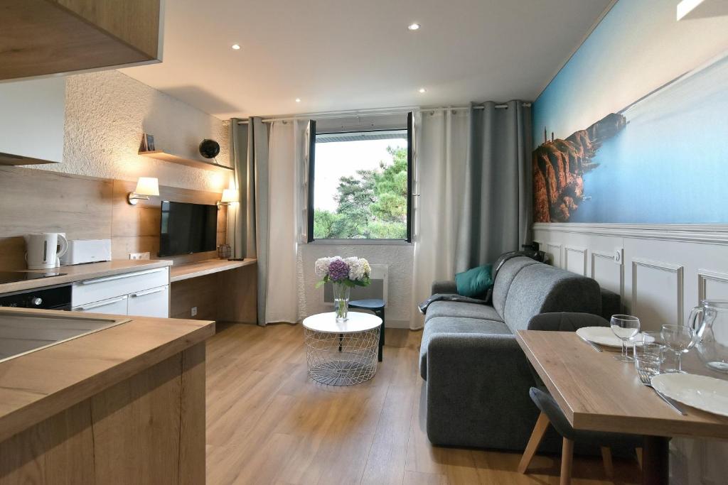 un salon et une cuisine avec un canapé et une table dans l'établissement Paulette 14 - A Sables d'Or les pins proche plage, à Fréhel