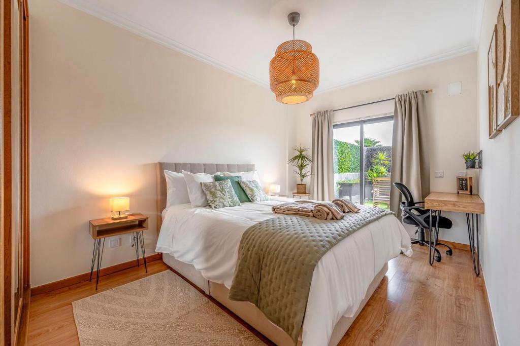 a bedroom with a bed and a desk and a window at Serenity Costa da Caparica in Almada