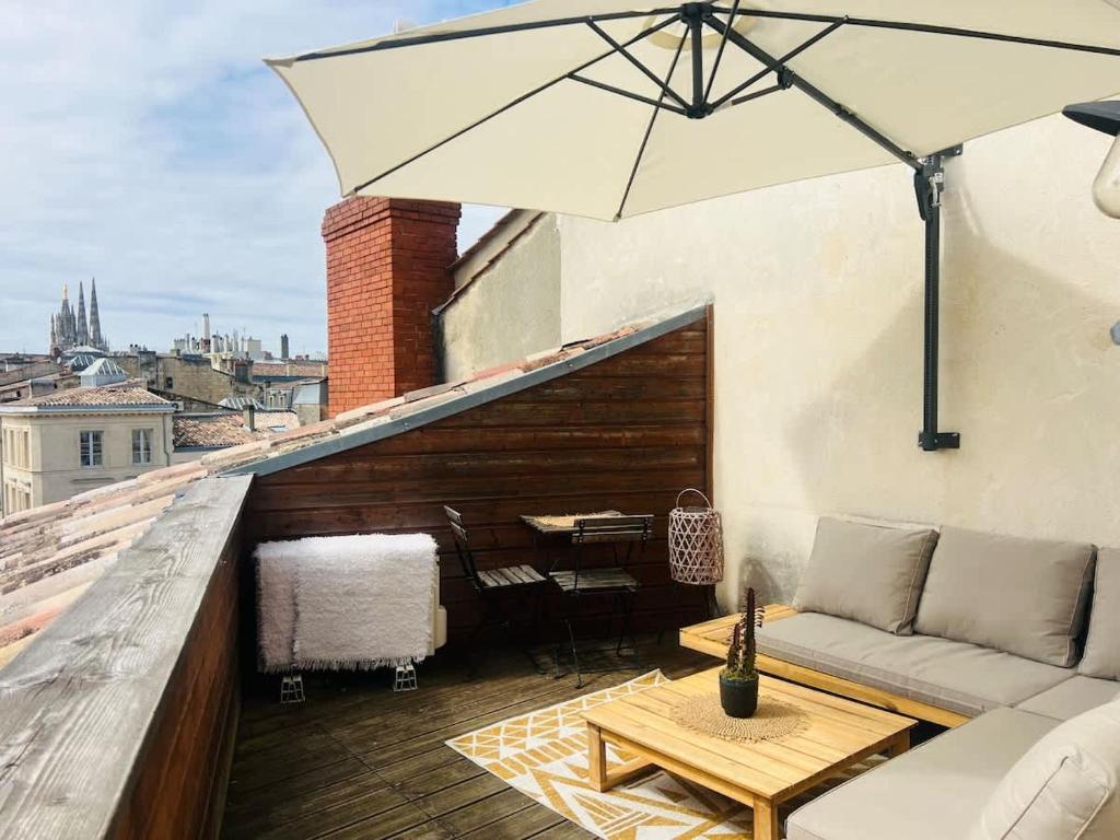 un patio avec une table et un parasol sur le toit dans l'établissement Rooftop dans l’hyper centre, à Bordeaux